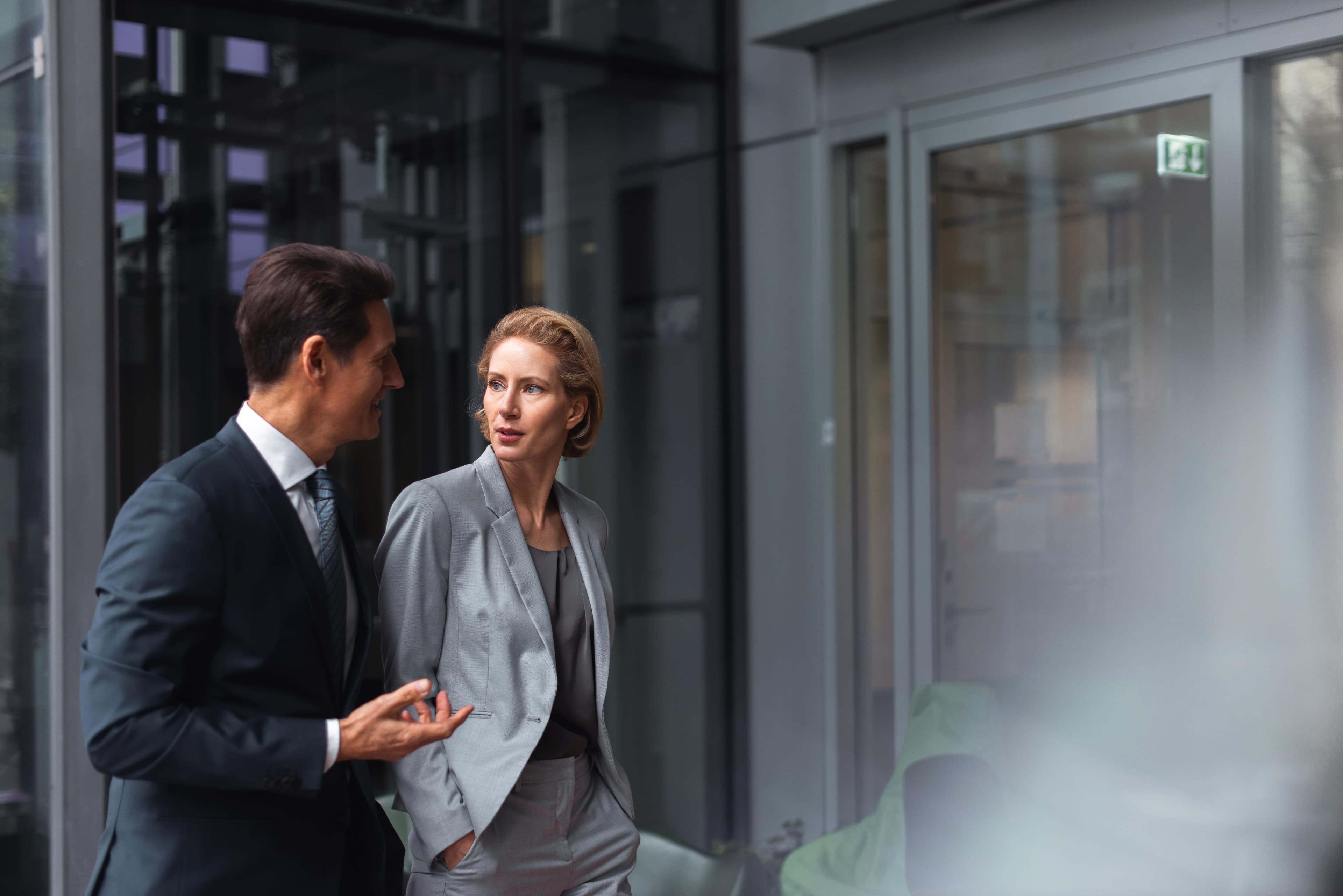 a business man and a business woman entering a building together